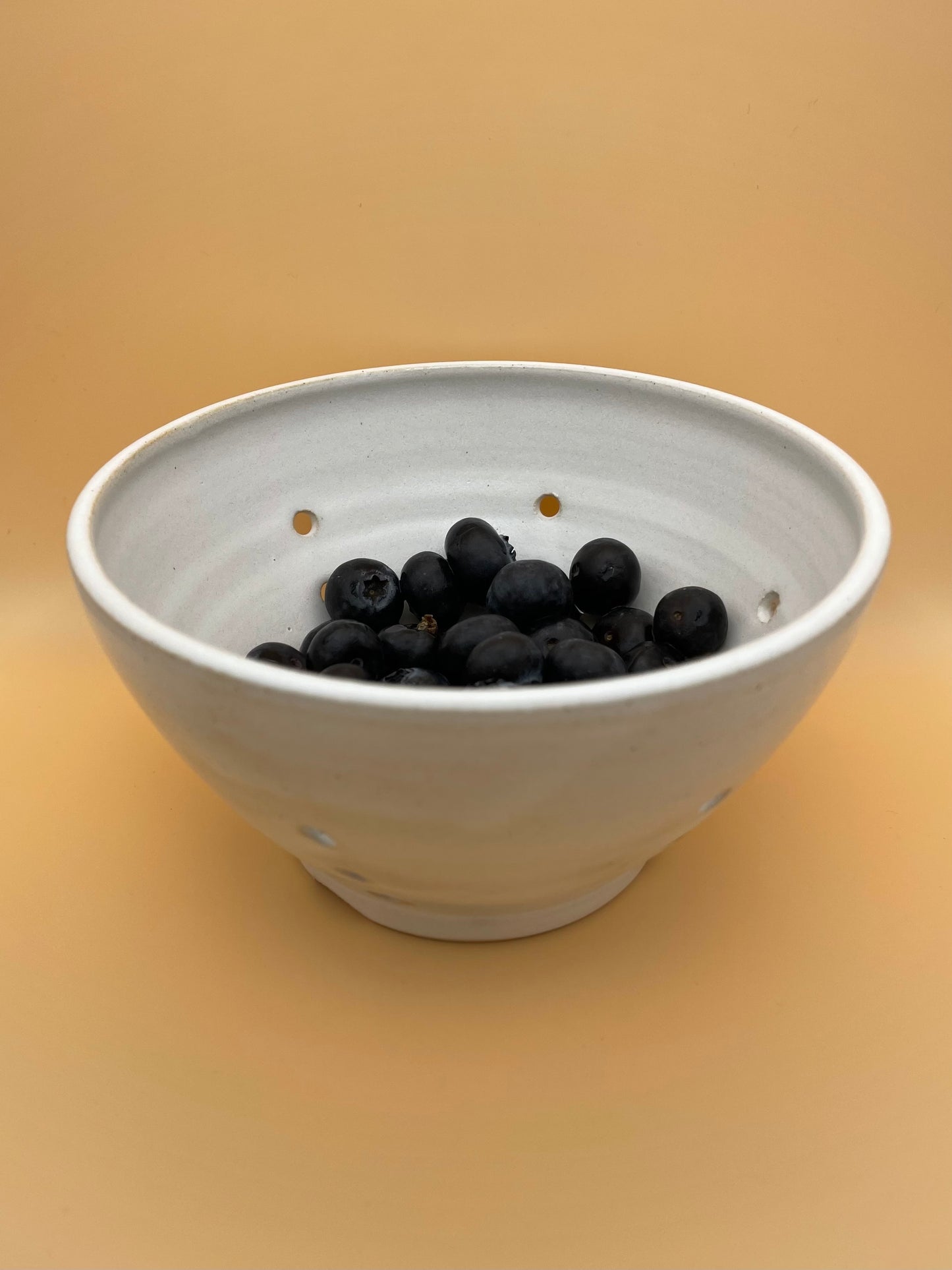 Handmade white ceramic berry bowl filled with fresh blueberries