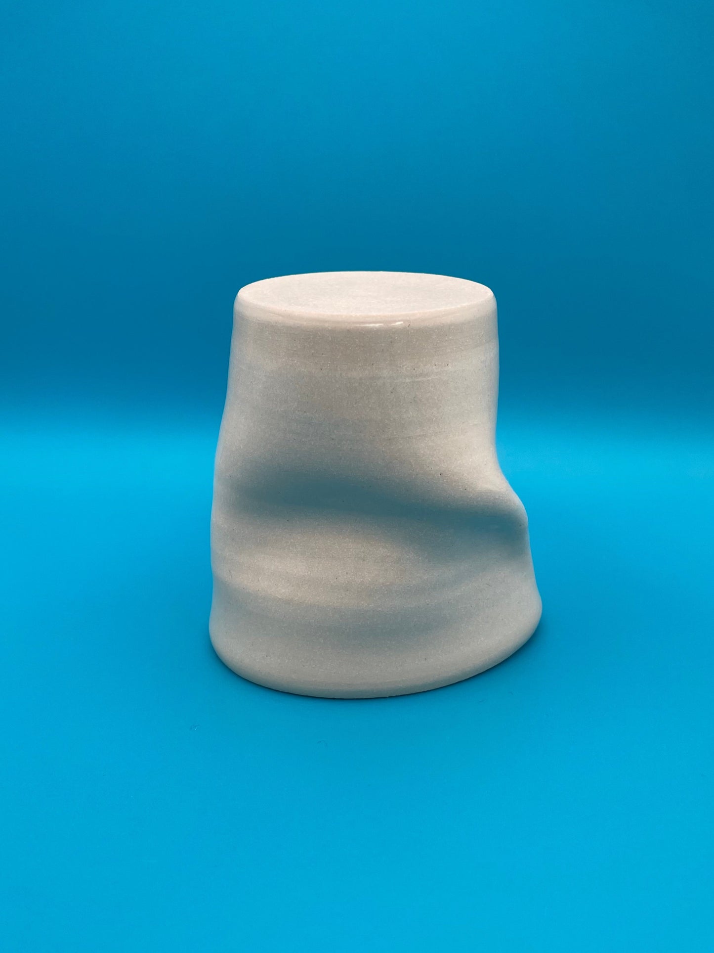 Non Paper Cup Crush – hand-thrown ceramic coffee cup with a crushed shape, made from stoneware clay and glazed with a transparent glaze, shown upside down