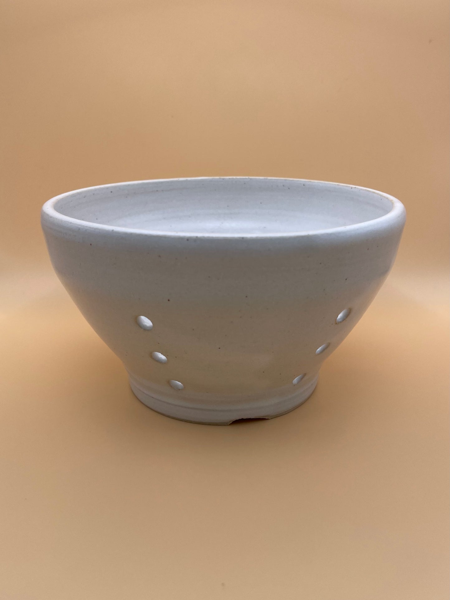 Side view of handmade white ceramic berry bowl showing curve and glaze finish